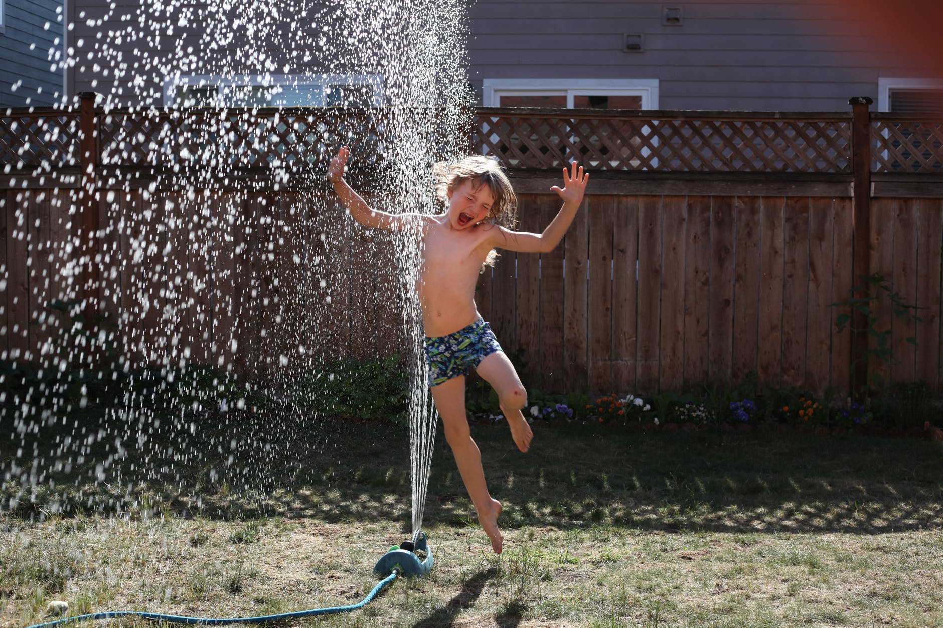 boy jumping near sprinkler